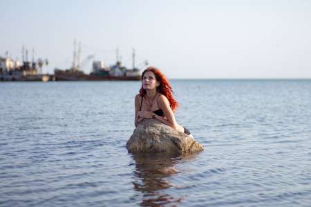 Рудоволоса красуня на камені в морі